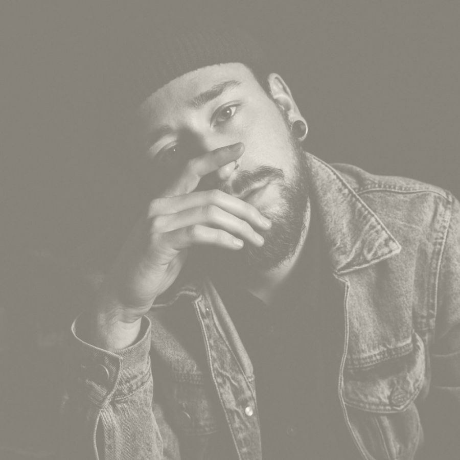 A contemplative man in a beanie and denim jacket, with a thoughtful expression, captured in monochrome tones.